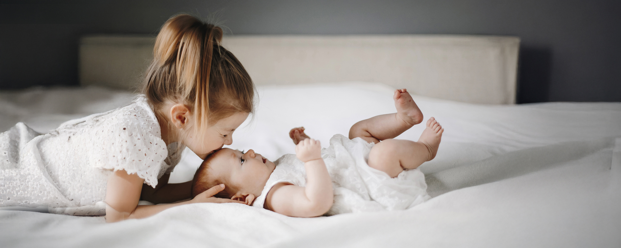 Blonde caucasian children on the white blanket dressed in white
